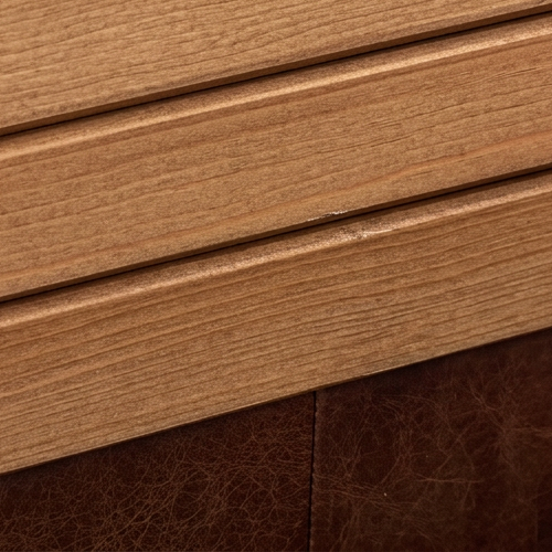 Close-up of grooved wood grain meeting a leather edge.